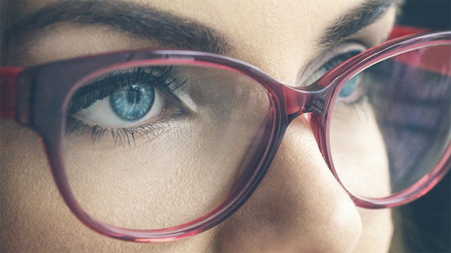 Macro shot of female blue eyes wearing glasses. Shallow DOF. Developed from RAW; retouched with special care and attention; Small amount of grain added for best final impression.16 bit Adobe RGB color profile.